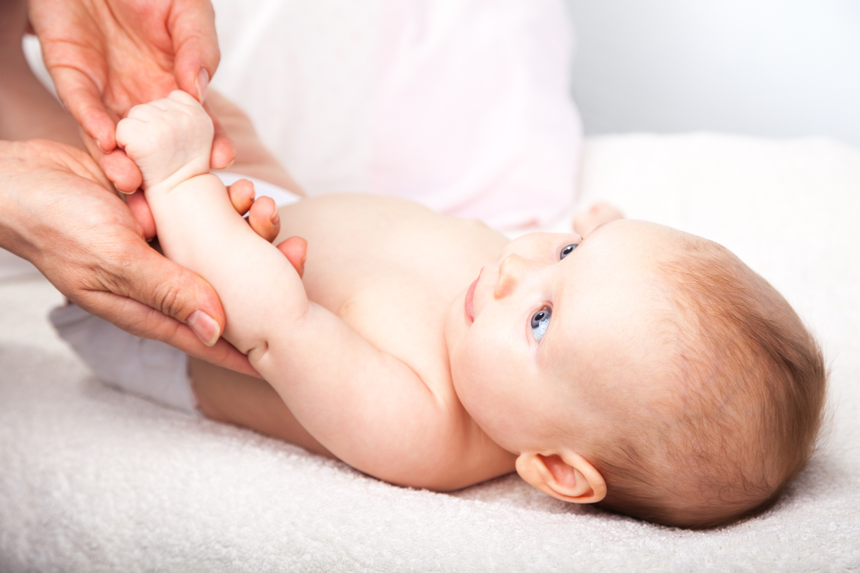Three month baby girl is receiving arm massage from a female massage therapist